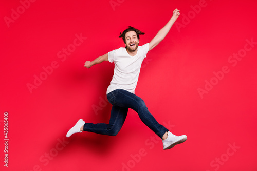 Full length profile side photo of young guy happy positive smile rejoice victory success go walk jump isolated over red color background