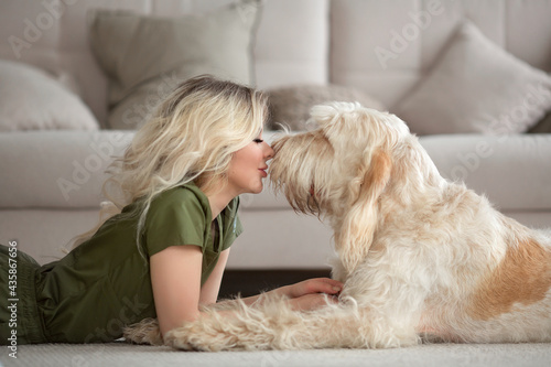 young beautiful woman with cute spinosa dog in the room. She wears vet uniform