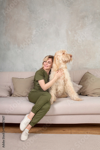 young beautiful woman with cute spinosa dog in the room. She wears vet uniform
