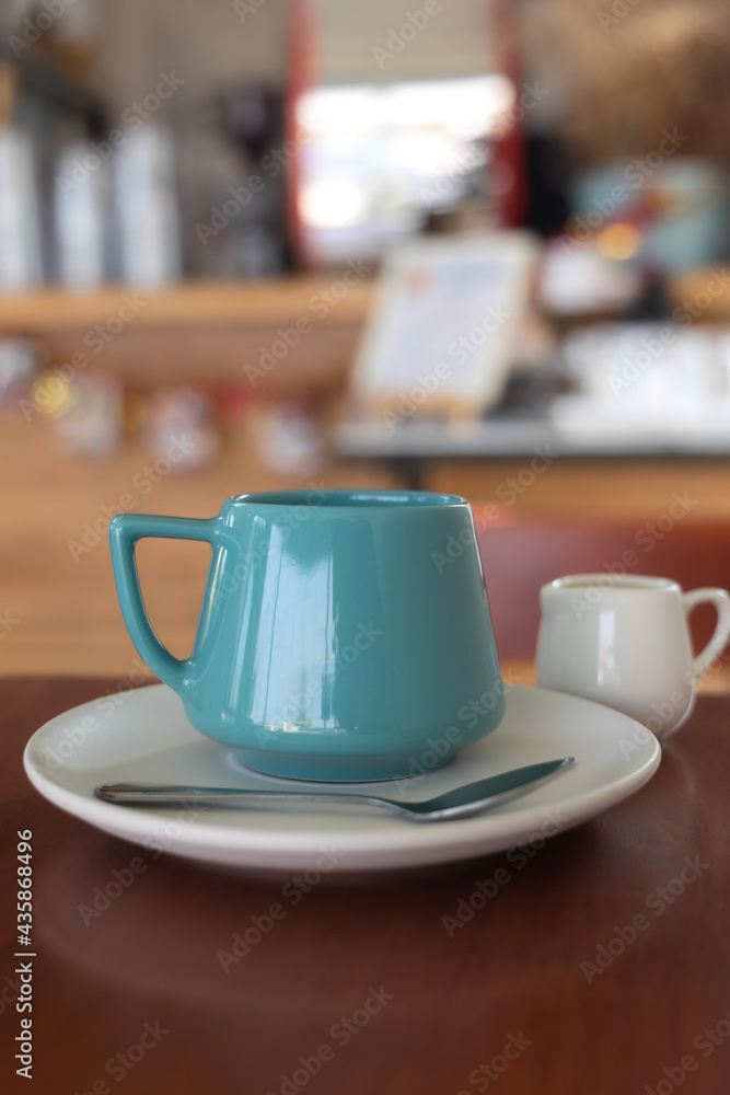 Blue vintage hot coffee mug with syrup cup placed on a wooden table in the coffee shop.