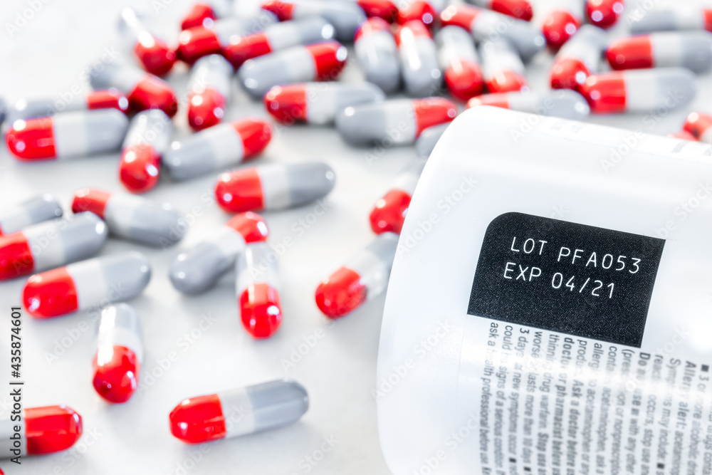 Expired date and lot number label print on medicine bottle with blurred  background of pile of old red-grey painkiller pills on table, awareness  expiration information from pharmaceutical manufacturing Stock Photo | Adobe