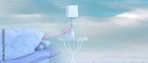 Woman arm on the bed turns off the alarm clock wake up, on blue winter clouds sky background. Putting alarm clock off in bedroom at home in the morning. Too early wake up from sleep concept