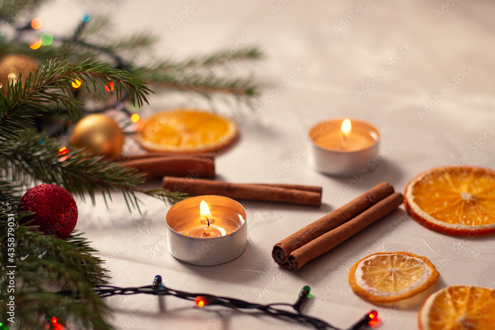 Obraz premium Christmas decorations on the table. Burning candles near the christmas tree branches, cinnamon and dried orange
