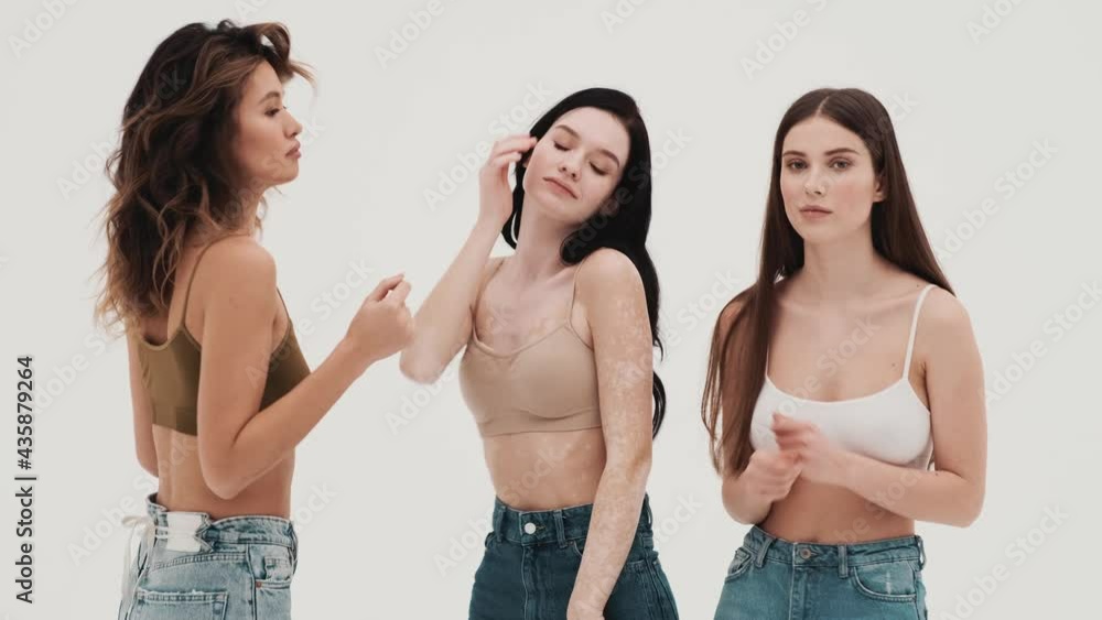 The three girls in knitted tops and jeans dancing in a white studio The three girls in knitted tops and jeans dancing in a white studio