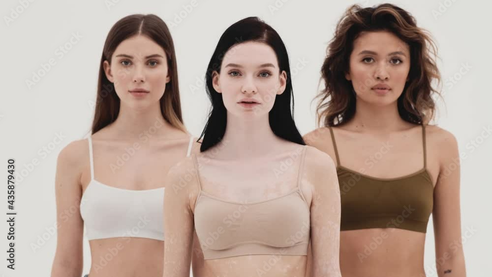 The three concentrated girls looking up at the camera while standing in a white studio The three concentrated girls looking up at the camera while standing in a white studio