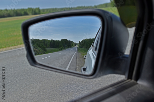 High-speed asphalt road in the reflection of the car mirror