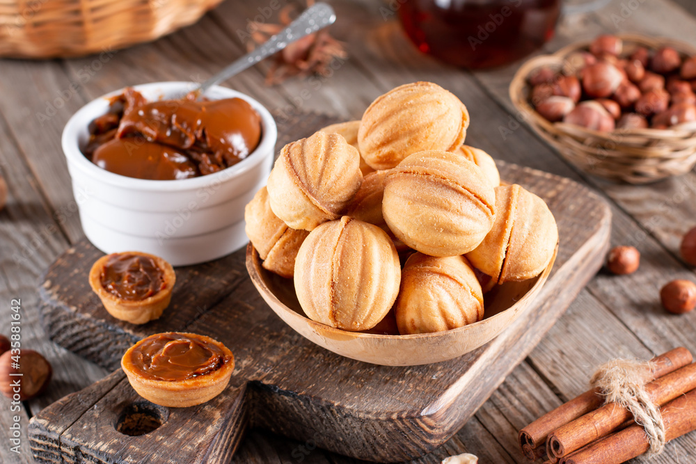 Delicious walnut shaped cookies filled with sweet condensed milk and nuts on old wooden background