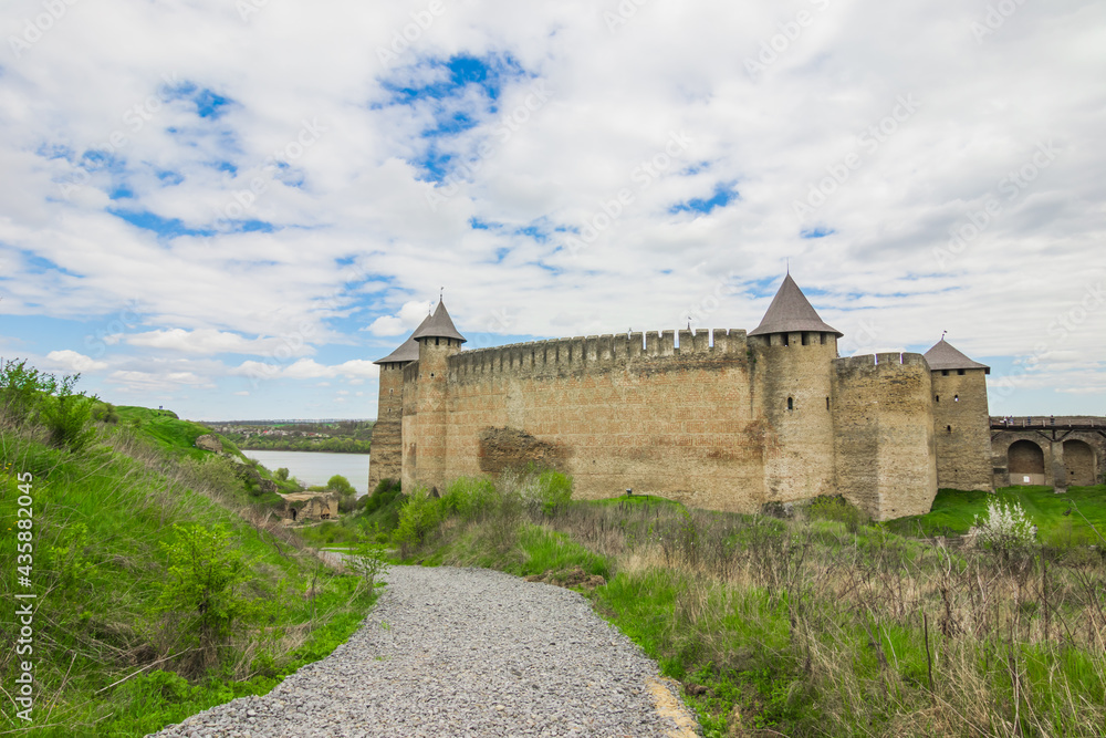 View of old castle Hotin near the river. Khotyn Fortress - medieval castle on yellow autumn hills. Ukraine, Eastern Europe. The architecture of the Middle Ages in our time.