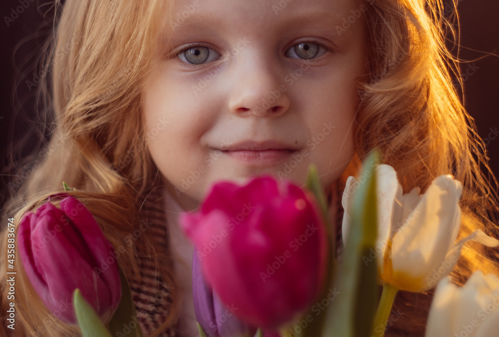 little girl with flowers tulips on a dark background little girl with flowers tulips on a dark background