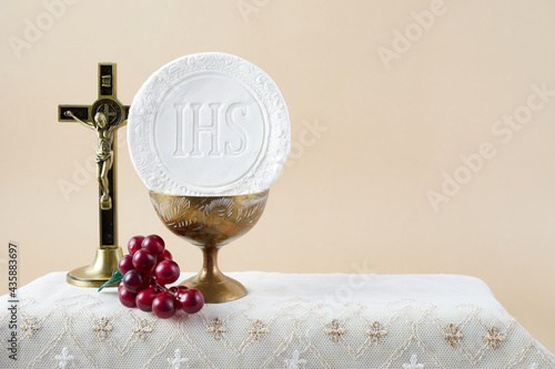 The Feast of Corpus Christi Concept. Holy communion and cup of glass with red wine on table. photo
