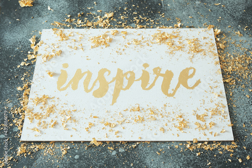 Inspire. Motivating lettering on white board. Handmade creativity. Gold letters. Gilding.