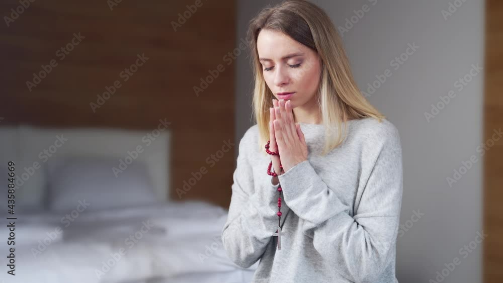 portrait young girl or woman sincerely praying on rosary at home ...