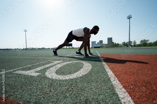 A male African American athlete prepares for a race at the stadium. At the start on the treadmill