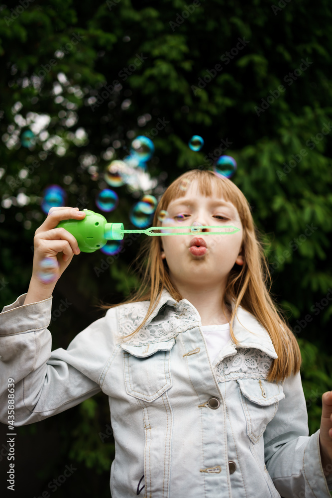 girl in a white denim jacket blowing soap bubbles girl in a white denim jacket blowing soap bubbles