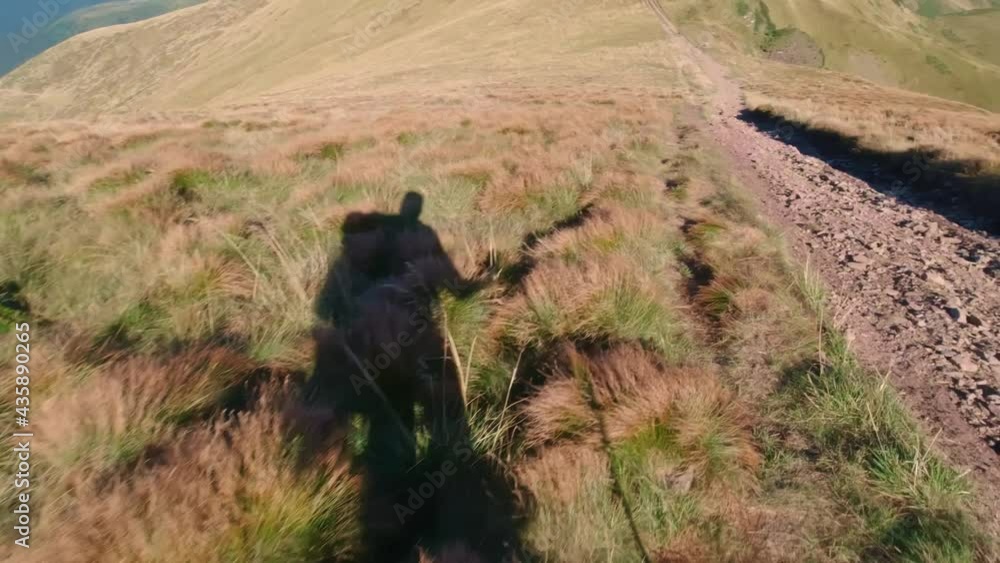 The shadow of a tourist who goes down the slope on a summer hike through the Ukrainian Carpathians. The shadow of a tourist who goes down the slope on a summer hike through the Ukrainian Carpathians.