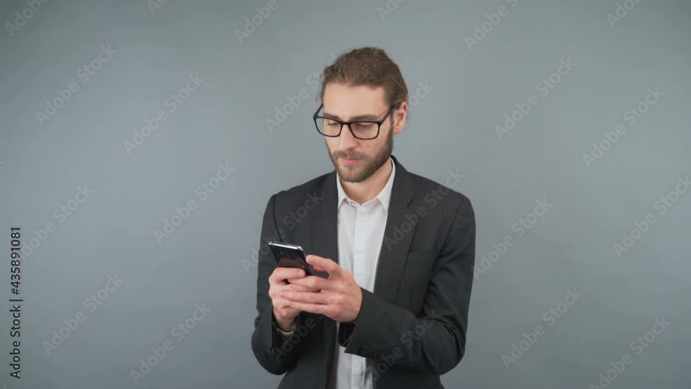 Businessman browsing information on the Internet. A man touches the smartphone screen. Man on isolated gray background in studio. 4K Businessman browsing information on the Internet. A man touches the smartphone screen. Man on isolated gray background in studio. 4K