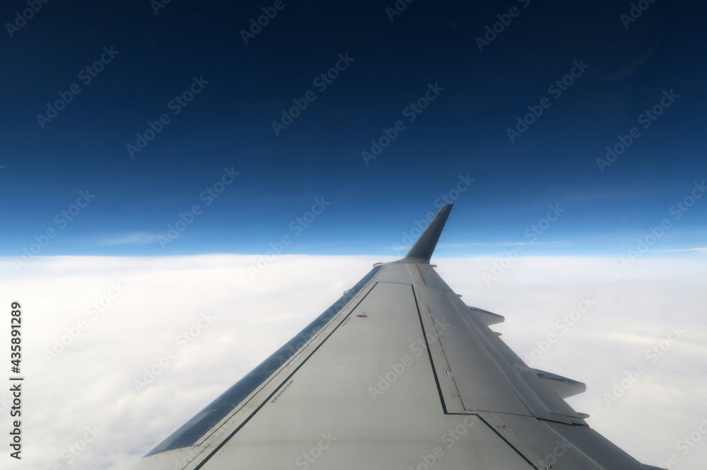 Skrzydło samolotu pasażerskiego w locie na tle nieba i chmur.