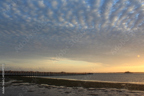 Scattered cloud lines over a fishing pier at sunset