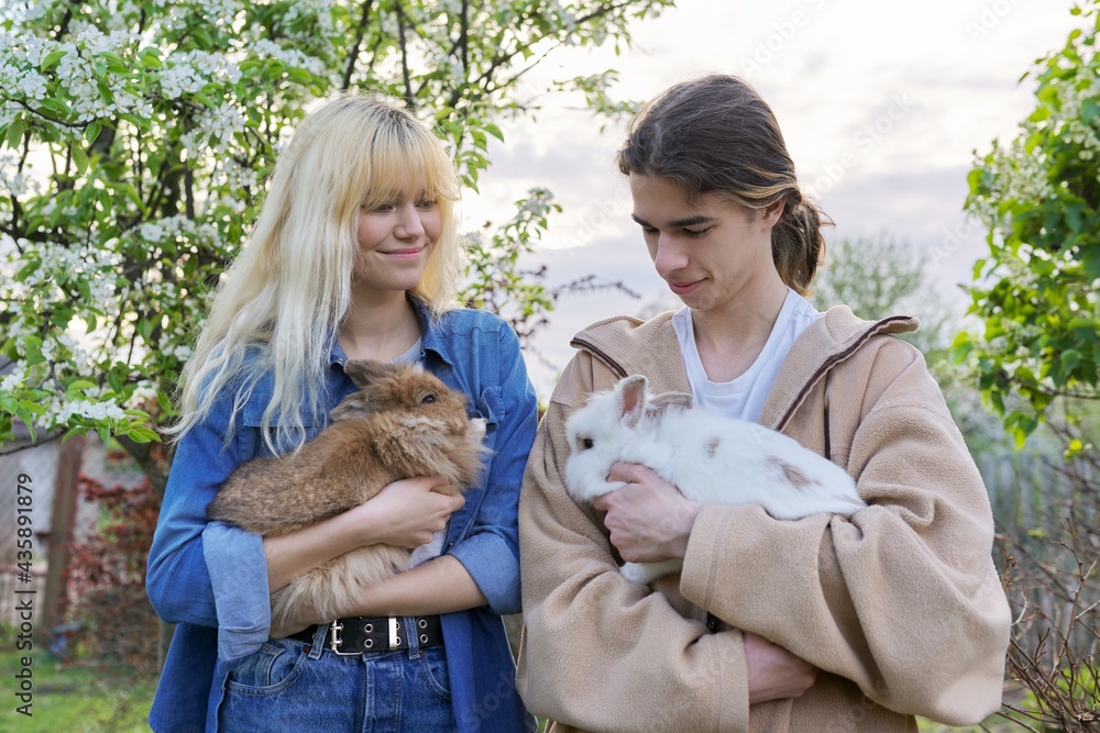 Teenagers with rabbits in their hands, pets a couple of decorative rabbits Teenagers with rabbits in their hands, pets a couple of decorative rabbits