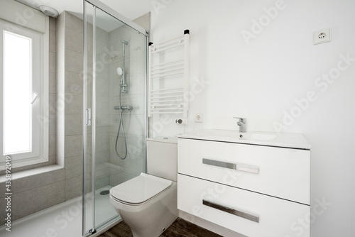 Photo of a bathroom with a bench sink cabinet  a white towel warmer wall radiator