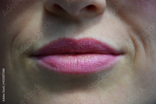 Close-up of painted with lipstick or lip gloss female lips and part of face