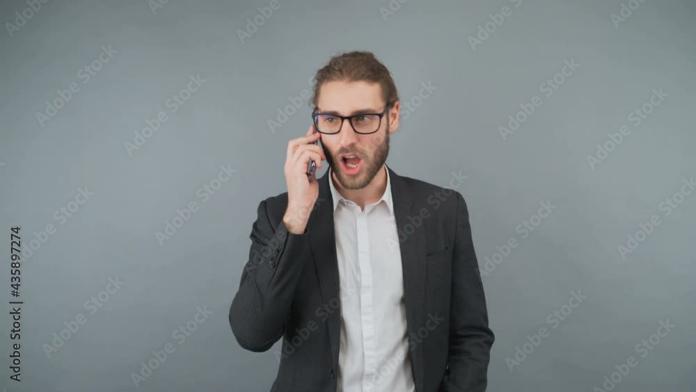 Businessman talking on the phone on an isolated gray background in the studio. 4K Businessman talking on the phone on an isolated gray background in the studio. 4K