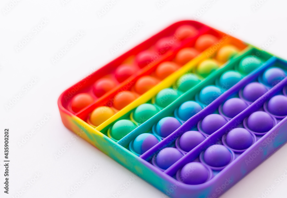 Close-up of pop it. Rainbow anti-stress toy on a white background. Selective Focus Close-up of pop it. Rainbow anti-stress toy on a white background. Selective Focus