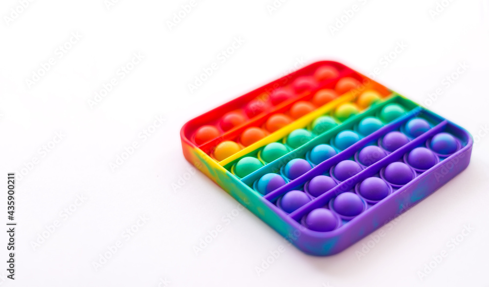 Close-up of pop it on a white background. Rainbow anti-stress toy. Selective Focus. Close-up of pop it on a white background. Rainbow anti-stress toy. Selective Focus.