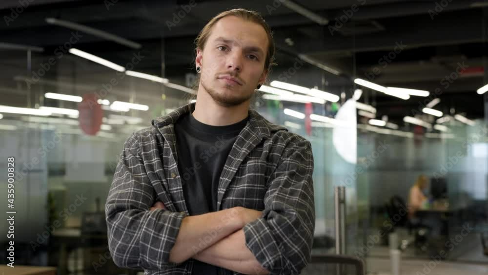 Young Handsome Man Standing In Workshop. His Hands Are Folded And He Is Smiling. Young Handsome Man Standing In Workshop. His Hands Are Folded And He Is Smiling.