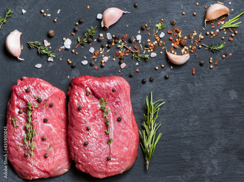 Two beef steaks with spices on a black background. Flat lay on gastronomic background