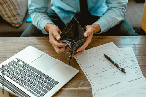 Man hands open empty purse looking for money.