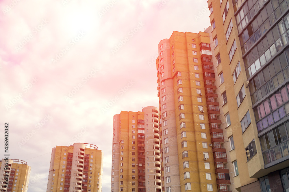 Fototapeta premium Dramatic red scenery of residential houses with street lanterns in front, evening sky with sun flare and distant spindrift clouds
