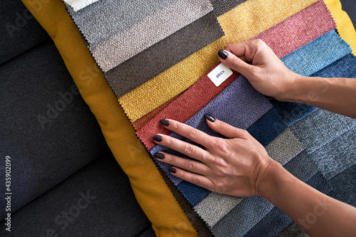 Obraz na płótnie Choosing upholstery fabric color and texture from various colorful samples in a store. Female customer hands touching textile. w salonie
