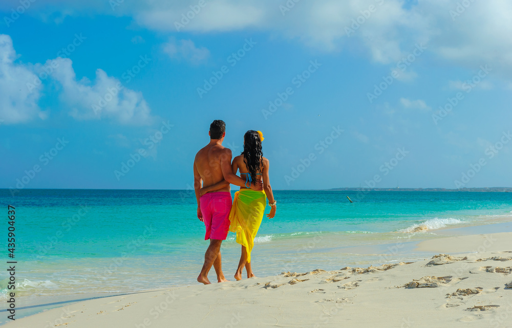 Couple at the beach, interracial, walking on the shore, holding hands