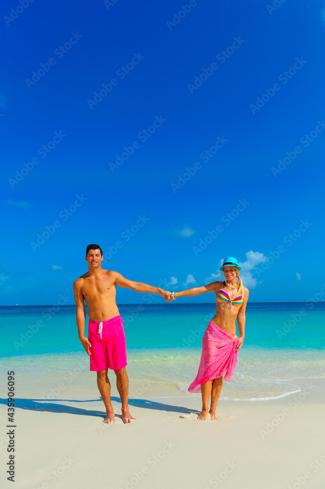 Couple at the beach, standng on the beach with pink outfits Couple at the beach, standng on the beach with pink outfits