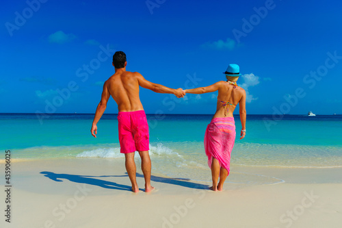 Couple at the beach, standng on the beach with pink outfits