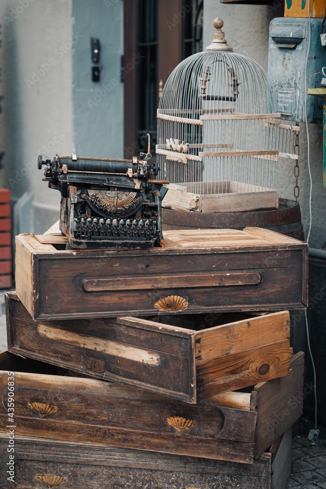 Old Typewriter standing on a wooden boxes next to cage for birds. Beautiful and stylish vintage items