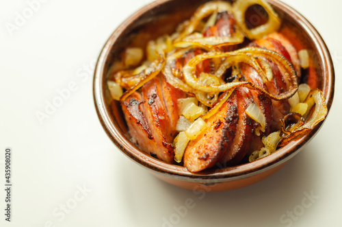 Traditionally roasted German sausage with onion served in a ceramic bowl