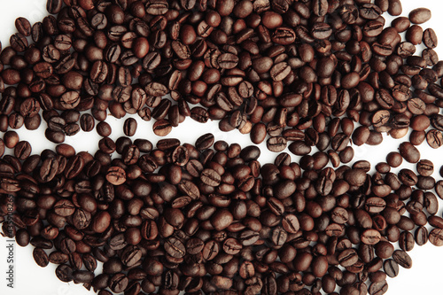 Roasted coffee beans laid out in the form of a large coffee grain close-up on a white background