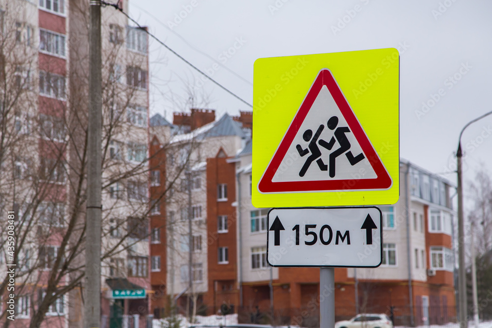 Close-up of caution children road sign in a residential area. City life and road traffic concept. Elements of a modern metropolis.