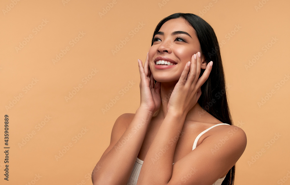 Young Asian woman with clean healthy glowing skin in white top isolated on beige background. Facial skin care concept, spa, cosmetology, plastic surgery. - obrazy, fototapety, plakaty 