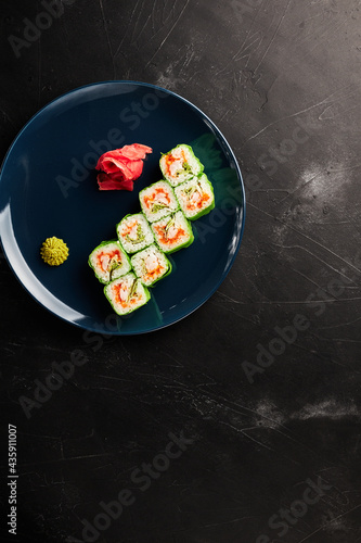 rolls in green rice paper in a blue plate on a black textured background