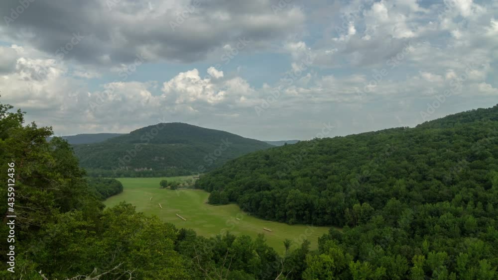 Timelapse of cloud movement over a mountain range, trees, and a field of grass Timelapse of cloud movement over a mountain range, trees, and a field of grass