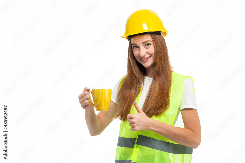 Red hair model in helmet and vest holding yellow mug with coffee Red hair model in helmet and vest holding yellow mug with coffee