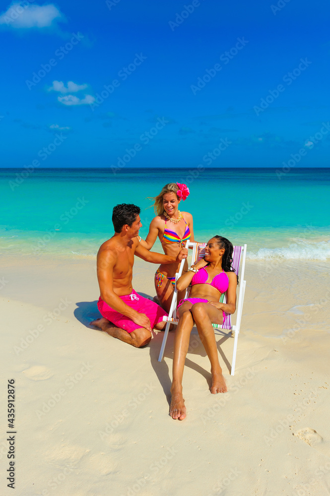 People at the beach, two girls and one guy relaxing, talking, sitting on beach chair, interracial, black