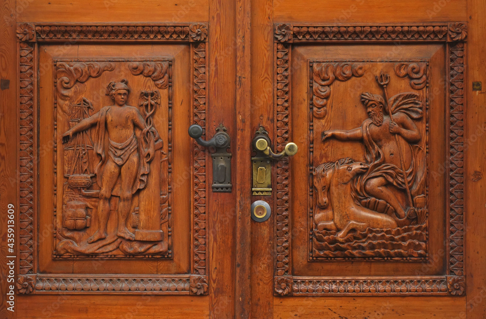 A detail of an old traditional wooden door on which is carved the figure of Poseidon and Mercury, in Trieste, Italy