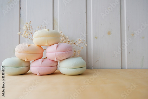 Macarons of different colors lie in a pyramid on top of each other on a light wooden background. The decor is made of white gypsophila flowers. Place for your text. photo