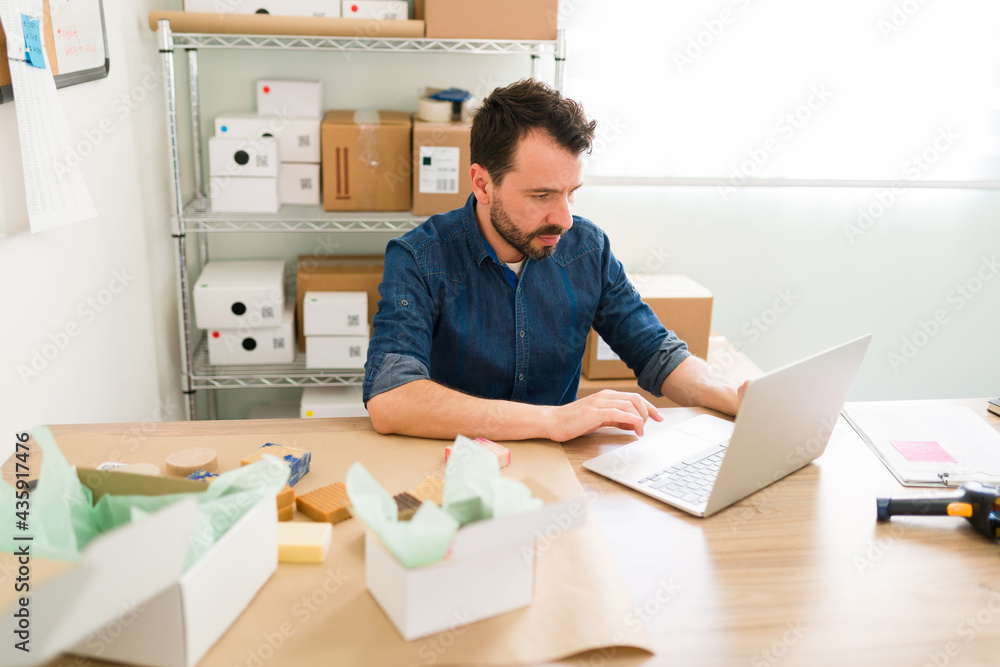 Focused business owner updating the online shop Focused business owner updating the online shop