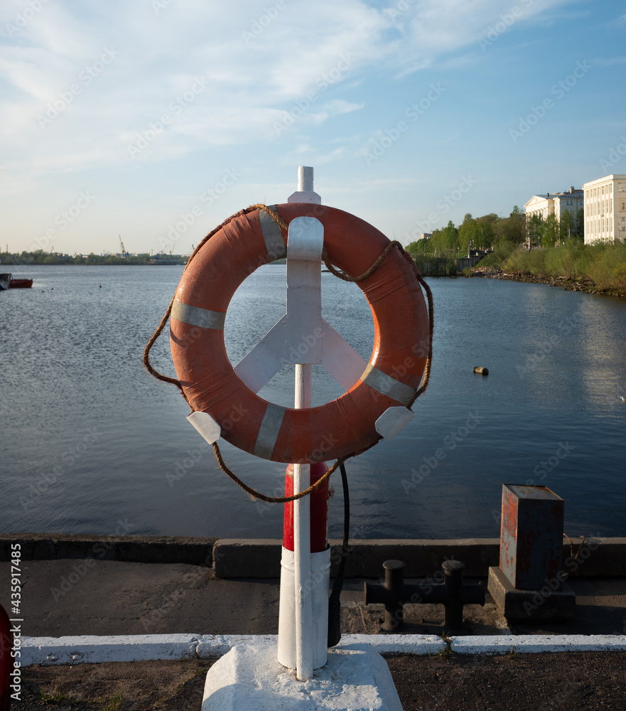 a life preserver hangs on the pier on the river bank.