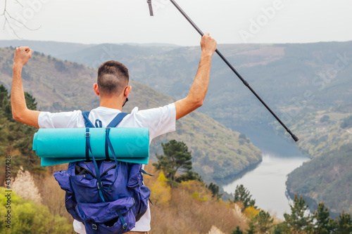 Tableau sur toile euphoric young man in the mountain with river landscape and arms raised